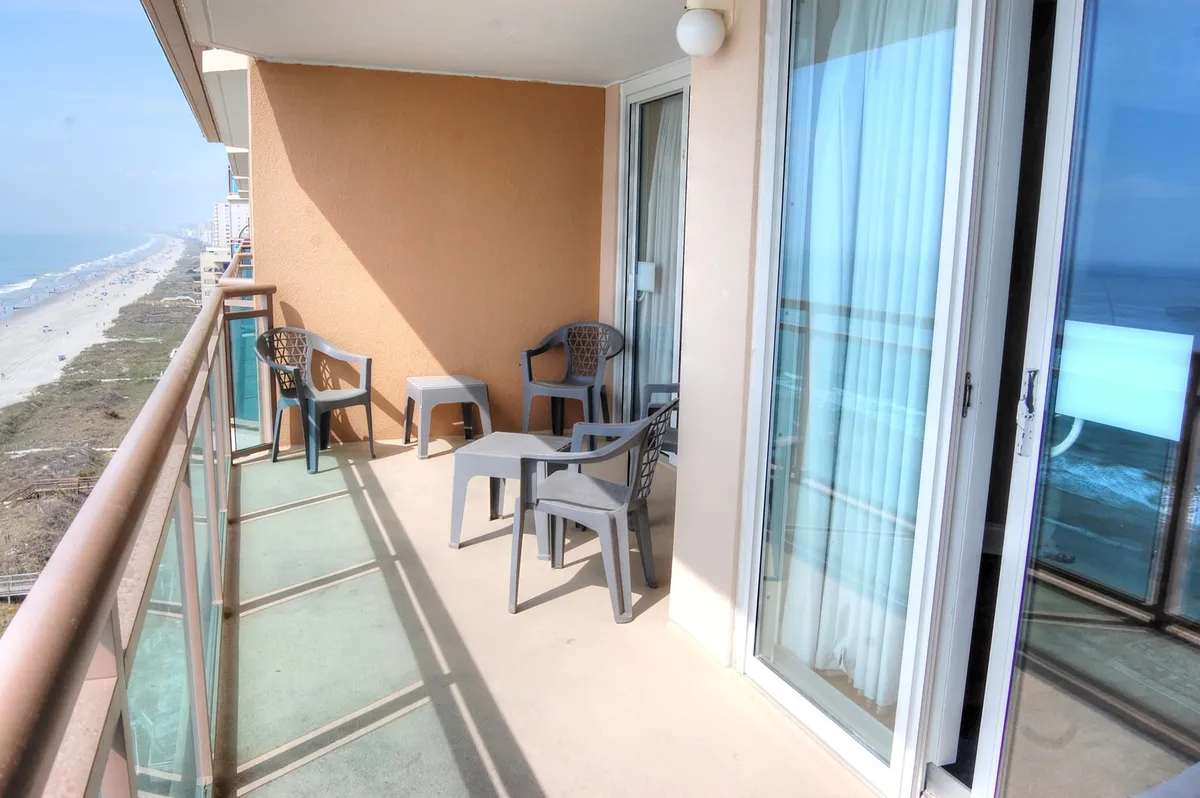 A serene balcony scene overlooking the ocean, with chairs perfectly positioned to enjoy the expansive water views. The soft sunlight and unobstructed horizon evoke a sense of tranquility and romance, ideal for couples seeking a relaxing escape.