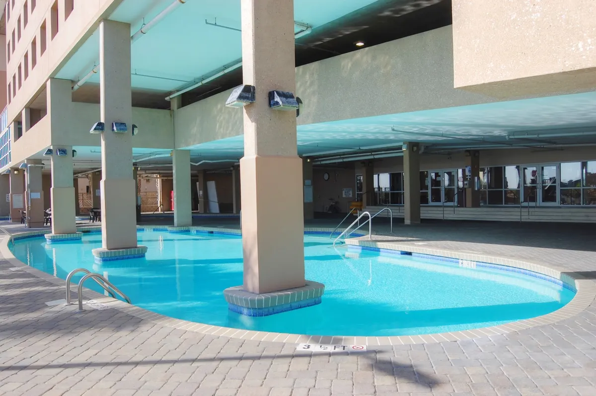 An inviting indoor pool area, featuring a sparkling pool edged by pillars and a comfortable seating area. The space is airy and relaxed – perfect for socializing, swimming, or unwinding with fellow residents during the cooler months.