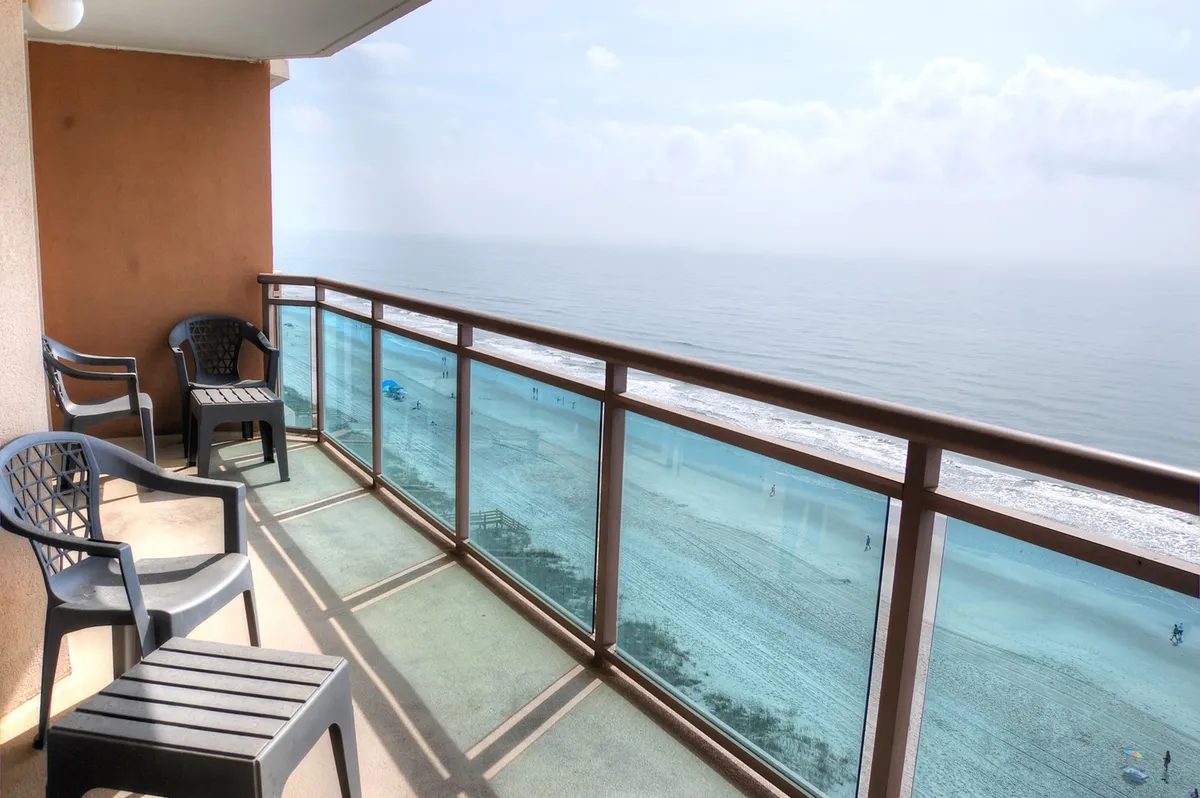 This exterior shot features a private balcony with railing, a stunning beach view, and a cozy seating area. The tranquil atmosphere invites guests to relax, watch the sunset, or enjoy a quiet moment after a day of adventures.