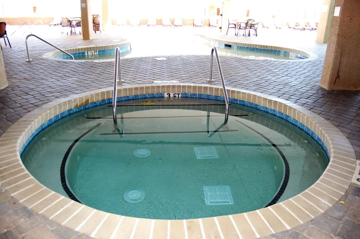 A stylish indoor hot tub area with spacious surrounding seating and elegant tile flooring. The tranquil mood is perfect for unwinding after a day of beach activities or on cooler days.